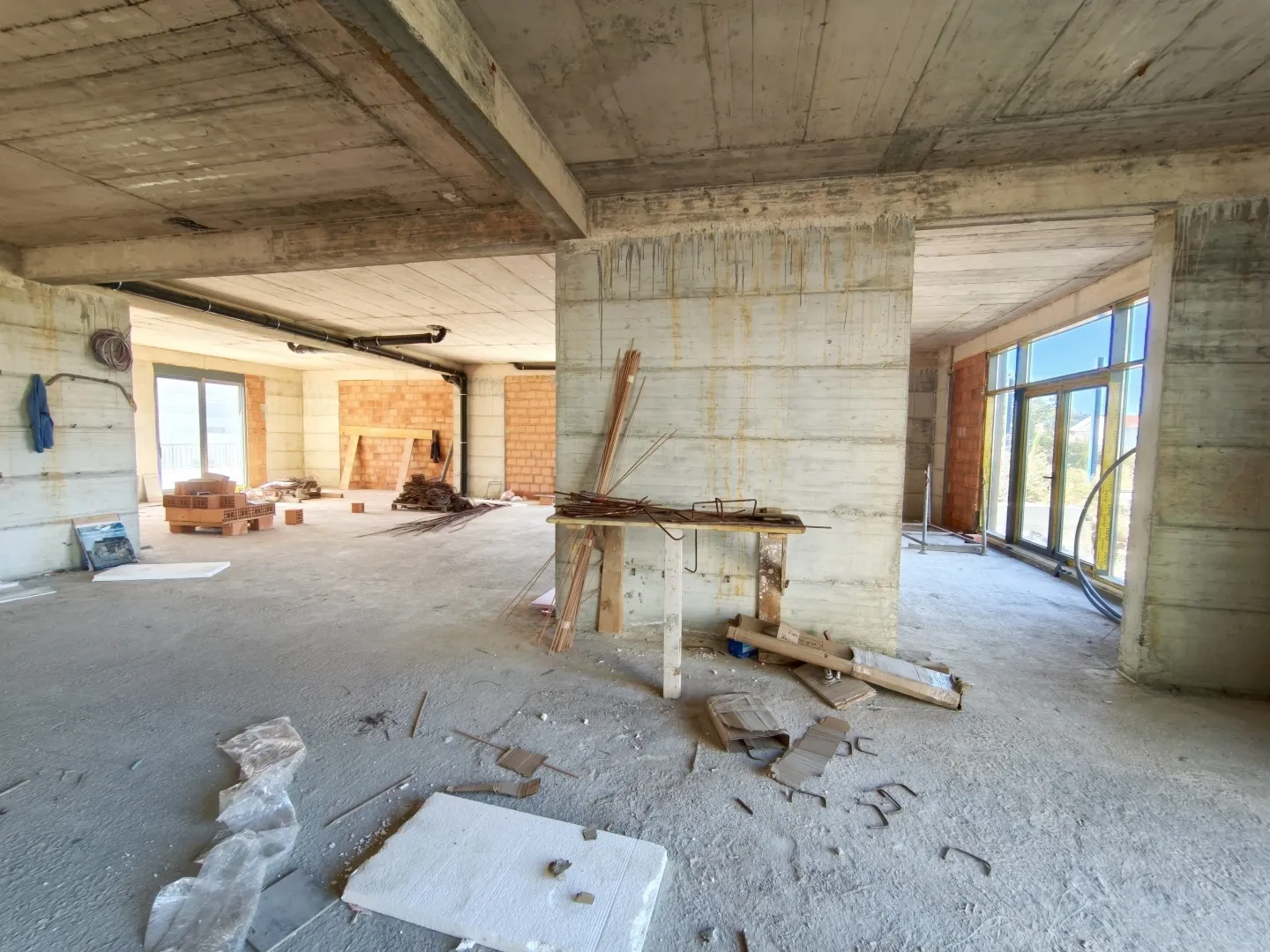 Unfinished interior in rough construction works with concrete pillars and open space.