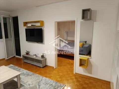 Living room with a TV and a view into the bedroom through the doorway. - image 8