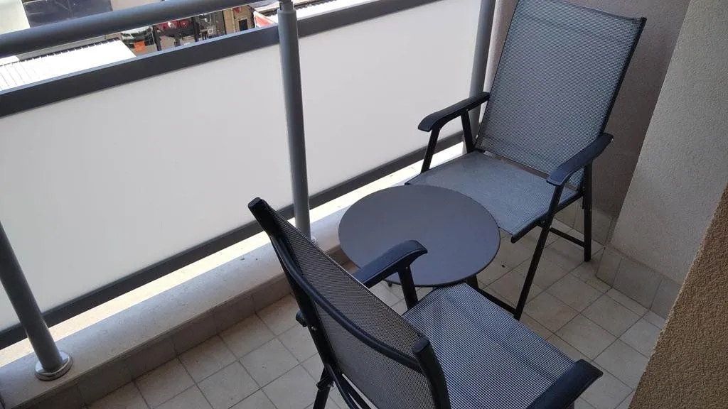 Small furnished balcony with a table and two chairs.