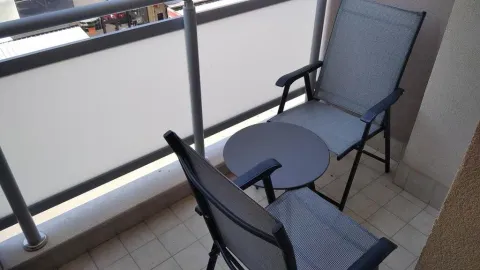 Small furnished balcony with a table and two chairs. - image 5