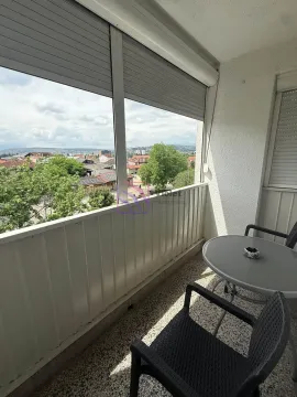 Covered balcony with seating set and city view. - image 4