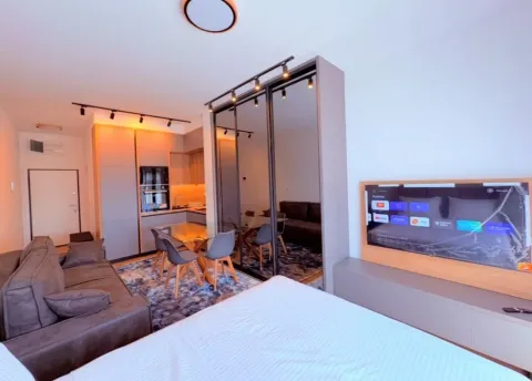 Modern living room with a sofa, TV, and dining area in an open space layout. - image 2