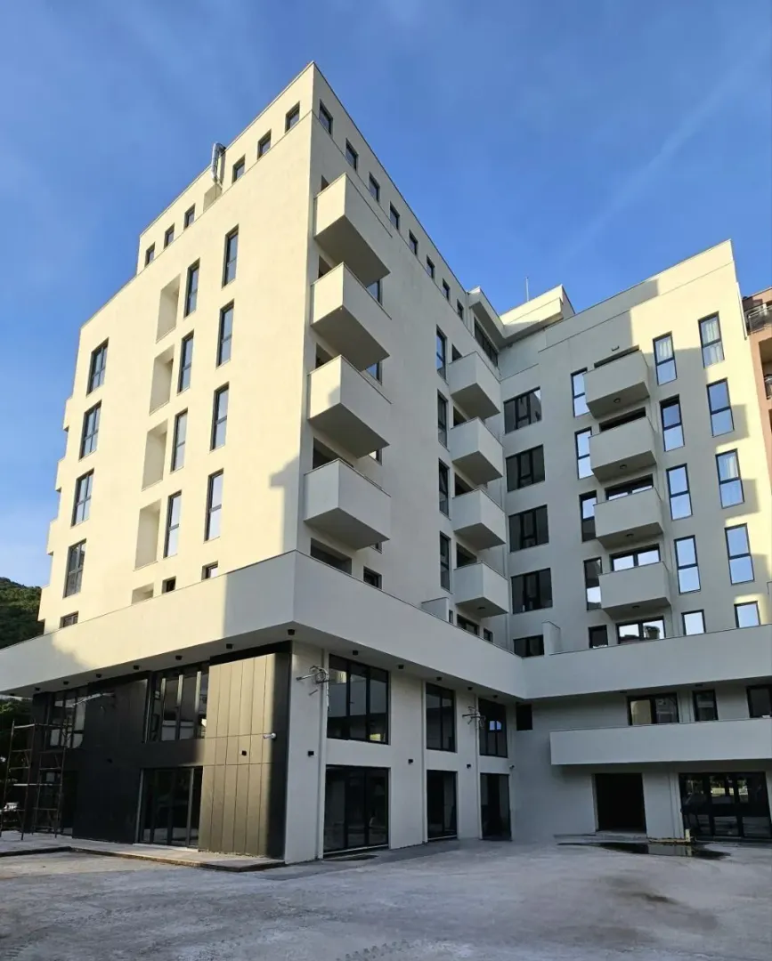 Eksterijer moderne stambene zgrade sa terasam i uređenim prizemljem.