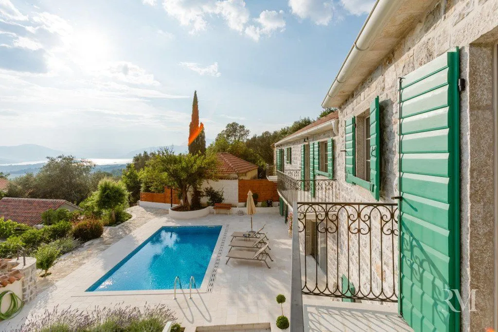Exterior of a traditional stone house with a swimming pool and sea view.