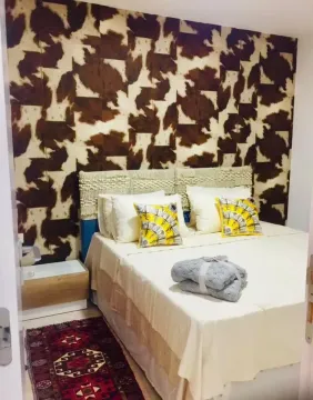 Furnished bedroom with a double bed and animal print wallpaper on the wall. - image 5