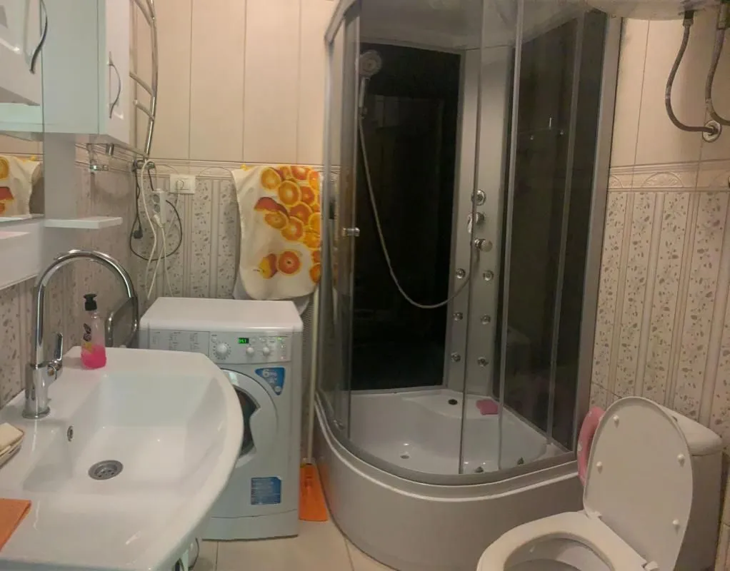 Bathroom equipped with a shower cabin, washbasin, toilet, and washing machine.