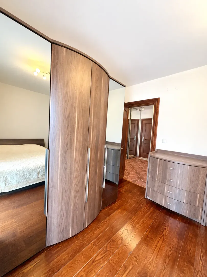 Bedroom with a large wooden wardrobe, bed, and wooden flooring.