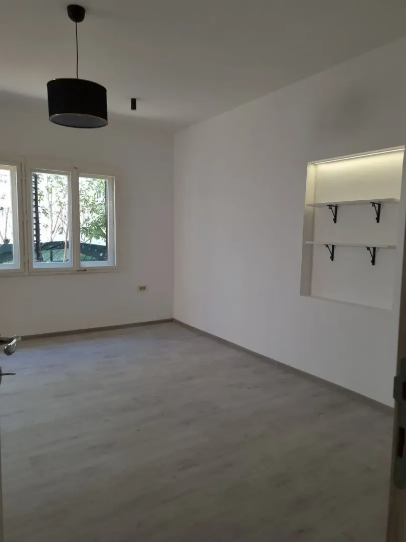 Empty bright room with white walls and wooden flooring.