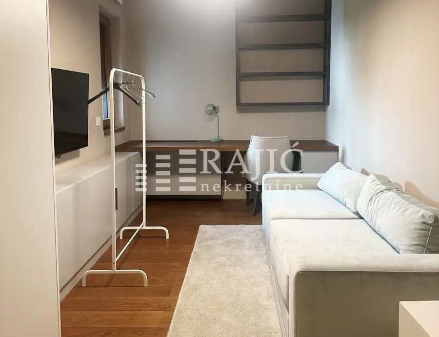 Small living room with a sofa, desk, and TV.