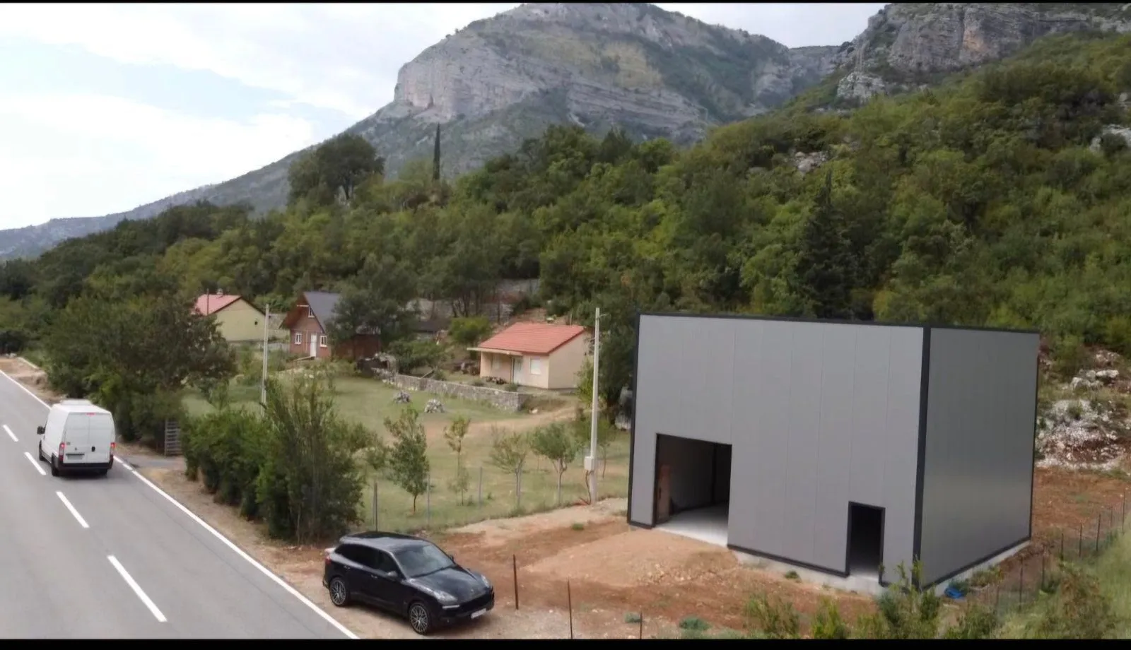 Aerial view of a building under construction with surrounding landscape and road.