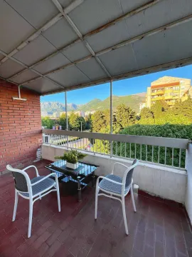 Covered balcony with outdoor seating and a view of the city and mountains. - image 6