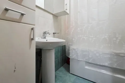 Small bathroom with a sink, white cabinet, and a bathtub with a curtain. - image 9