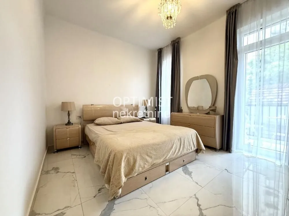 Spacious bedroom with a double bed, nightstands, and a dresser.