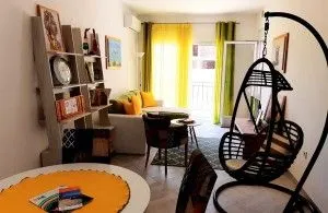 Living room with a sofa, dining table, and hanging chair.