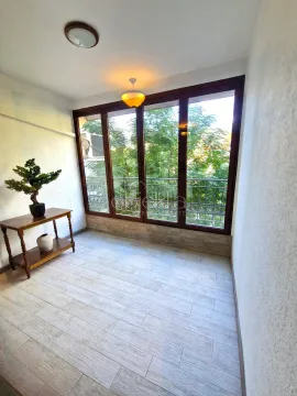 Enclosed balcony with a wooden console table and a view of greenery. - image 6