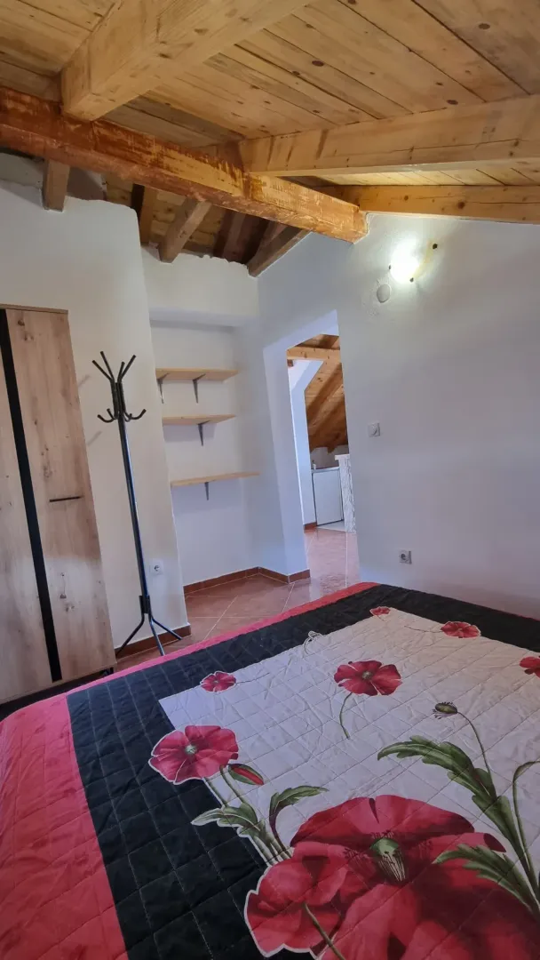 Spavaća soba sa krevetom, drvenim plafonom i ormarom.