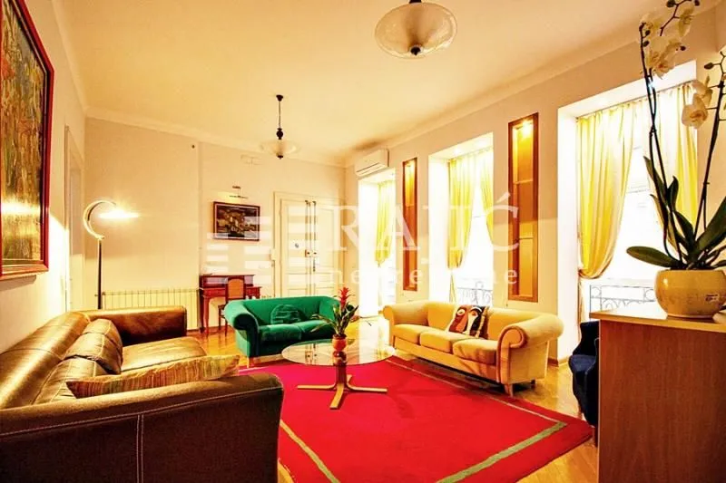 Spacious living room with seating furniture and a rug.