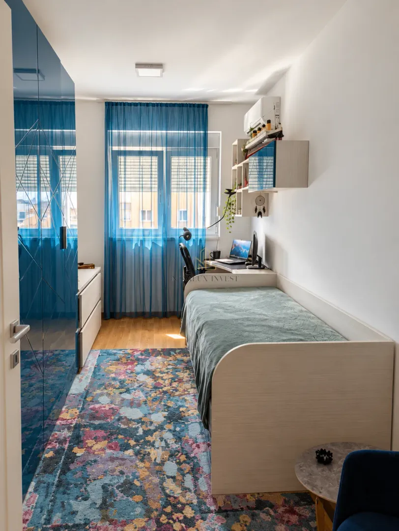 Small bedroom with a bed, desk, and blue wardrobe.