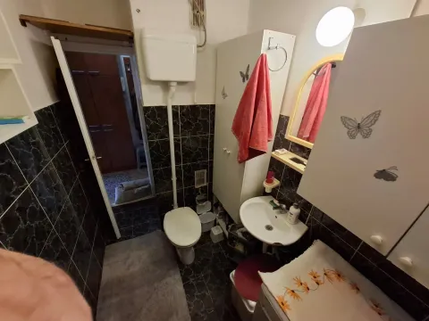 Manje kupatilo sa umivaonikom, WC šoljom i tamnim pločicama. - image 7