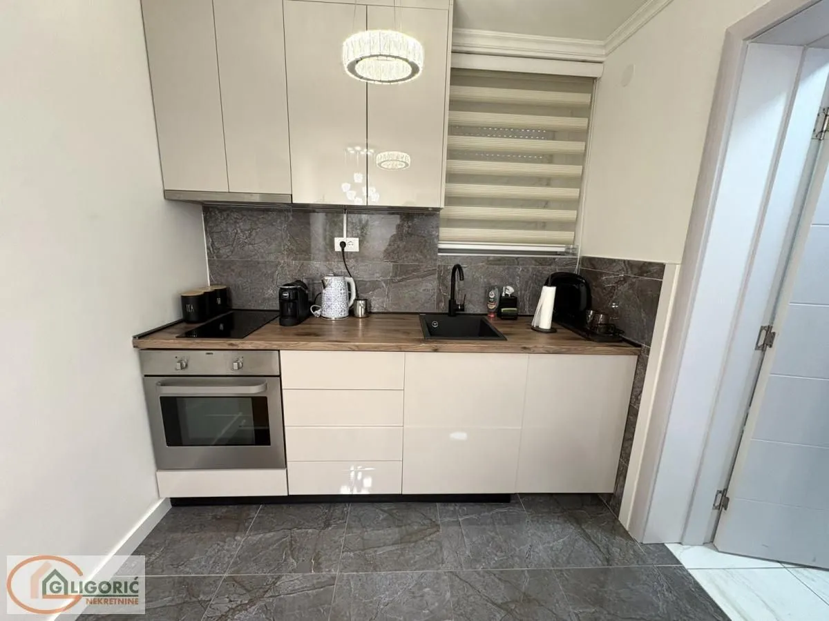 Compact modern kitchen with white cabinets and built-in appliances.
