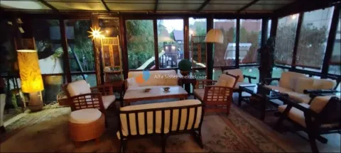 Spacious glass-enclosed living room with seating furniture and a view of the yard. - image 8