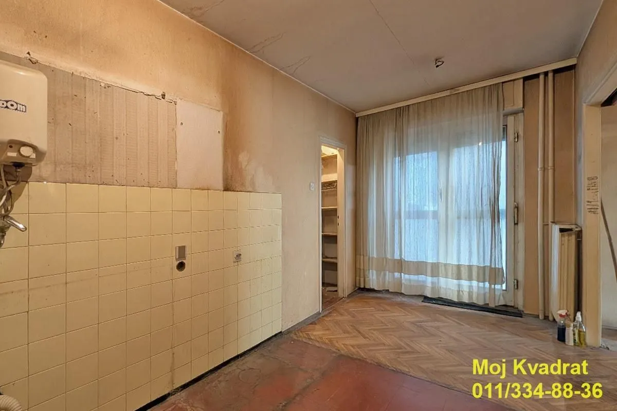 Starija kuhinja sa pločicama i izlazom na terasu.