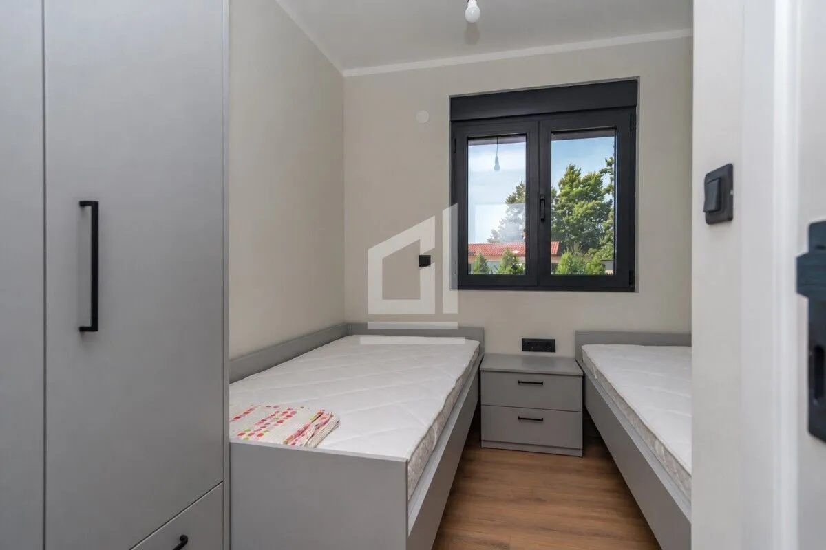 Small bedroom with two single beds, a wardrobe, and a window.