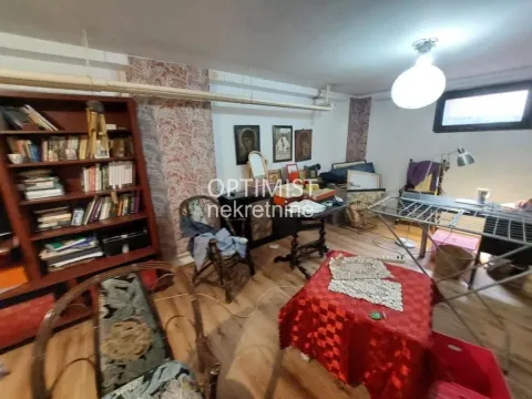 Dnevna soba ispunjena nameštajem, policama sa knjigama i dekorativnim detaljima. - image 15