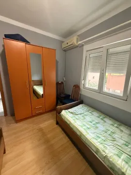 Manja spavaća soba sa krevetom, drvenim ormarom i prozorom. - image 10