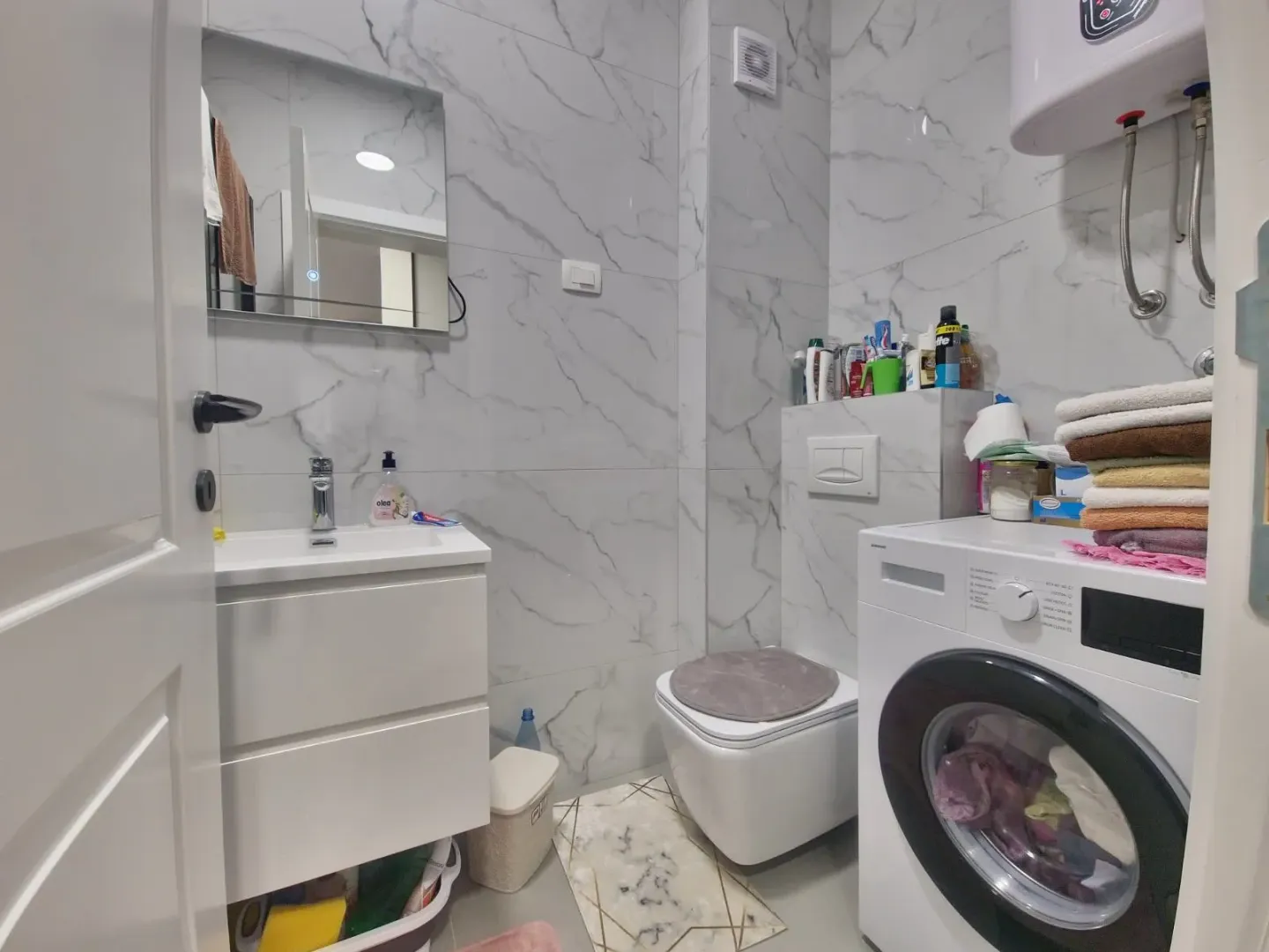 Smaller bathroom with a washbasin, toilet, and washing machine.