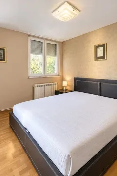 Furnished bedroom with a double bed, window, and radiator. - image 8