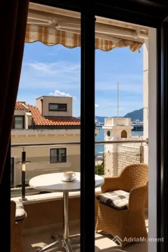 Namješten balkon sa stolom, stolicama i pogledom na more i okolne zgrade. - image 5