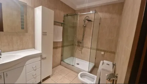 Bathroom with a glass shower and white cabinets. - image 13