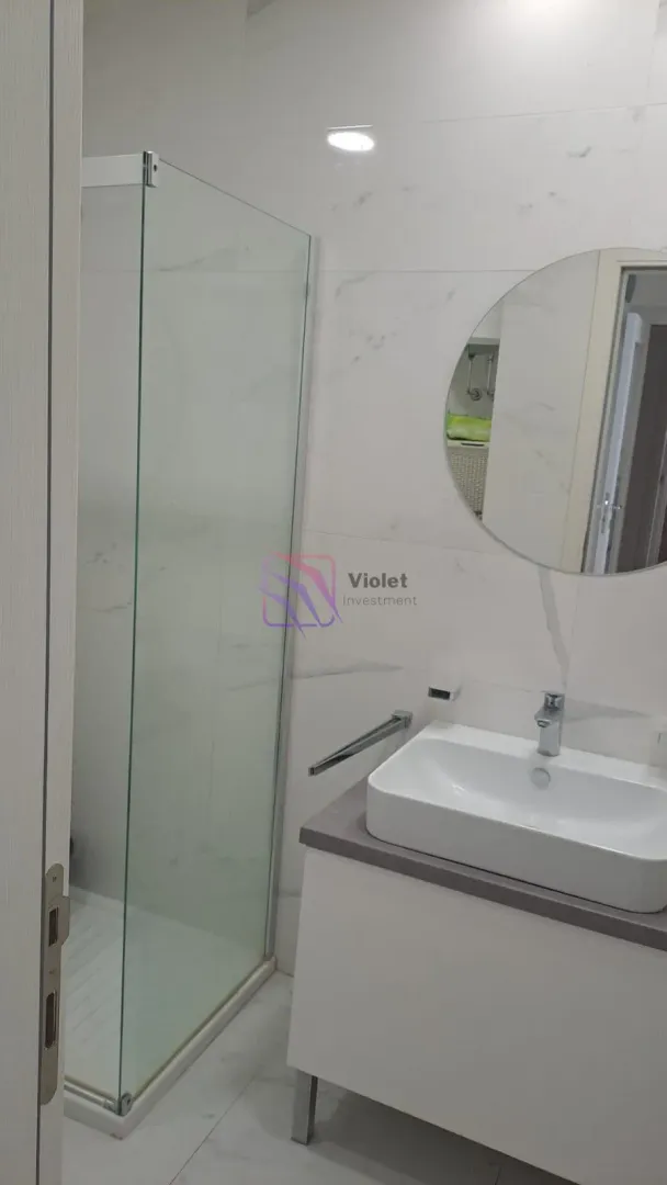 Modern bathroom with a shower cabin and a washbasin with a mirror.
