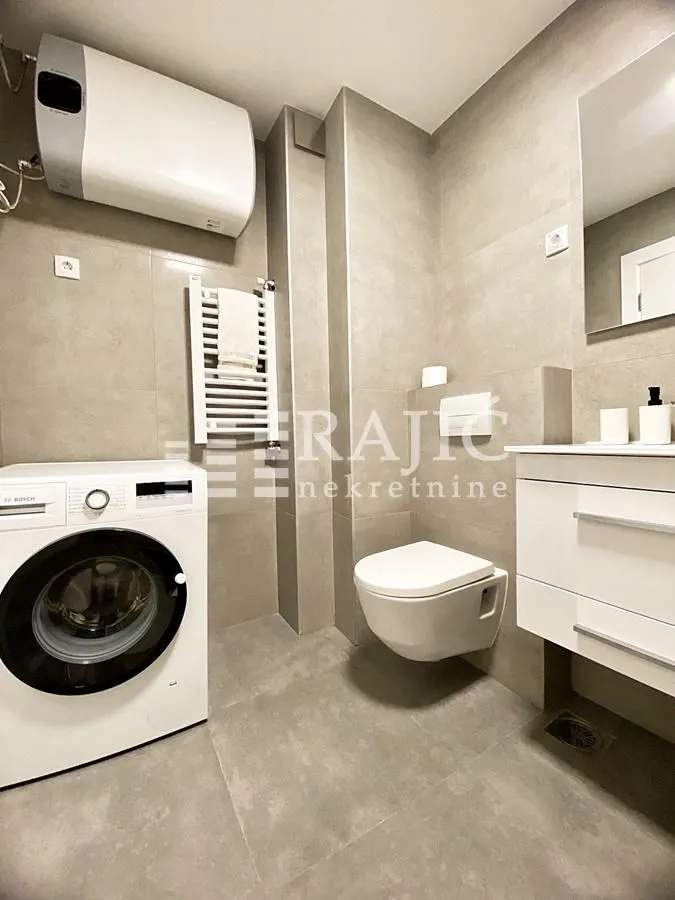 Modern bathroom equipped with a walk-in shower, washbasin, and washing machine.
