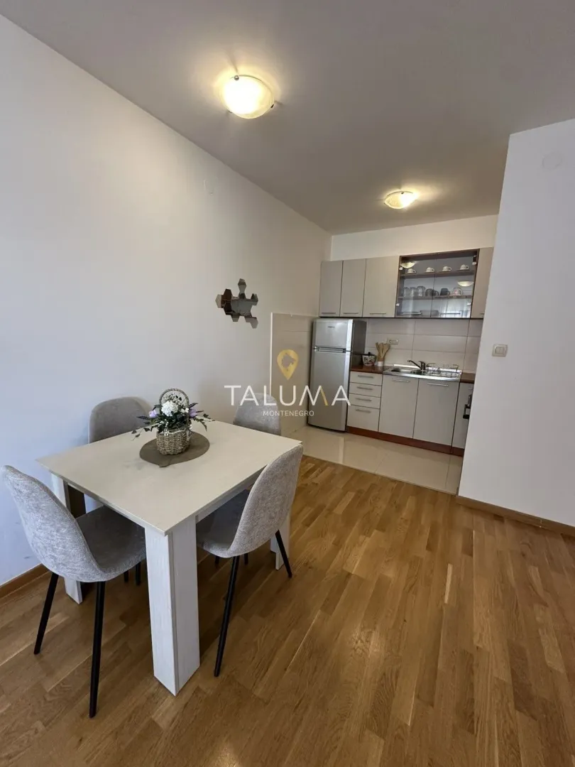 Dining area with a dining table and chairs and a kitchen in the background.