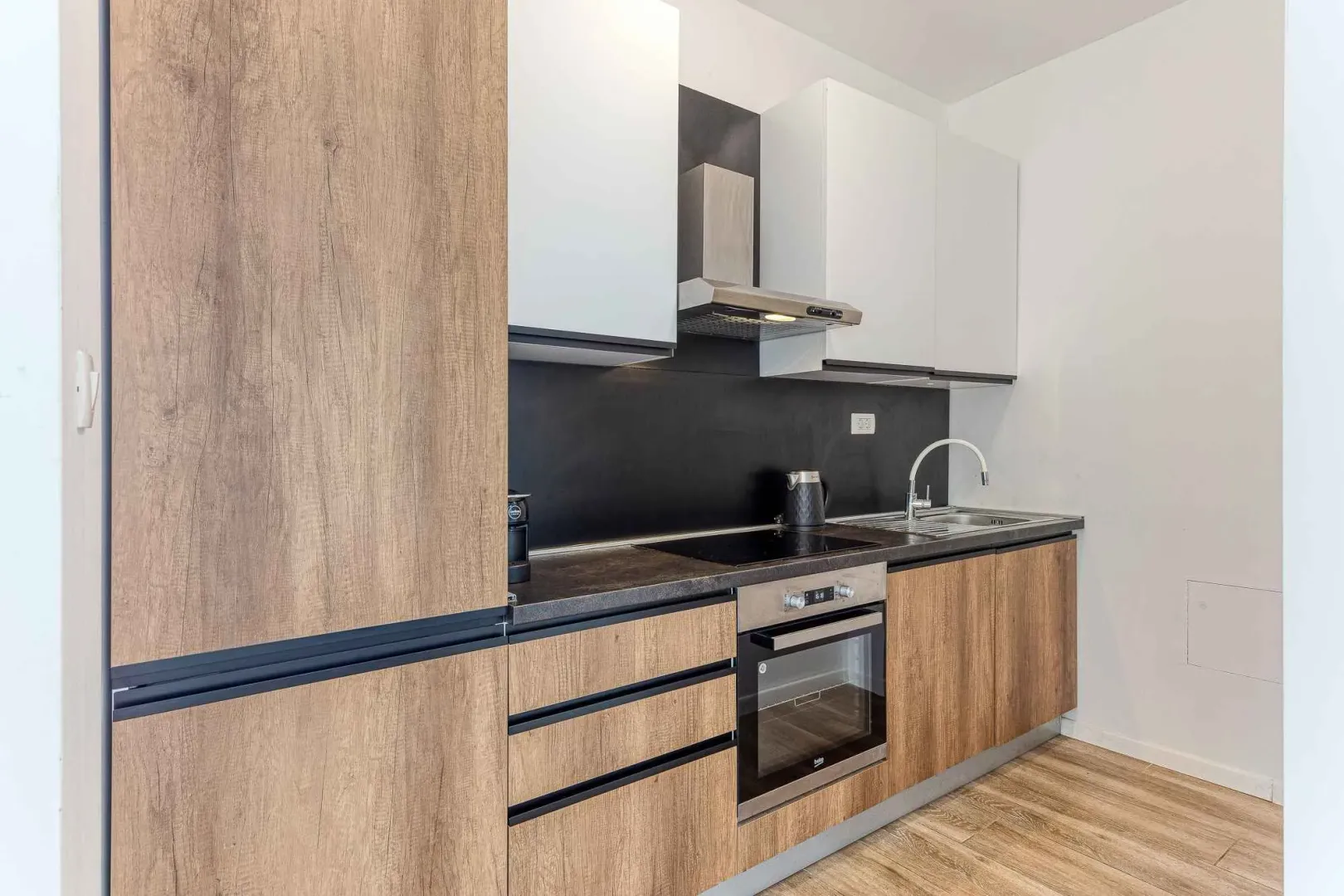 Modern kitchen with wooden elements, built-in oven, and hob.