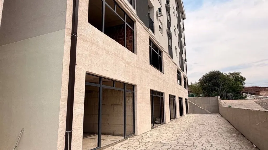 Exterior of ground floor commercial space in a new residential building with a paved yard.