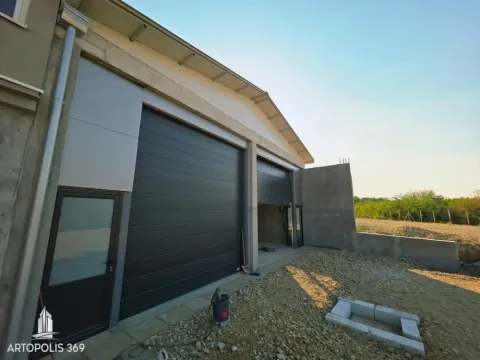 Exterior view of the building with garage doors and driveway under construction. - image 4
