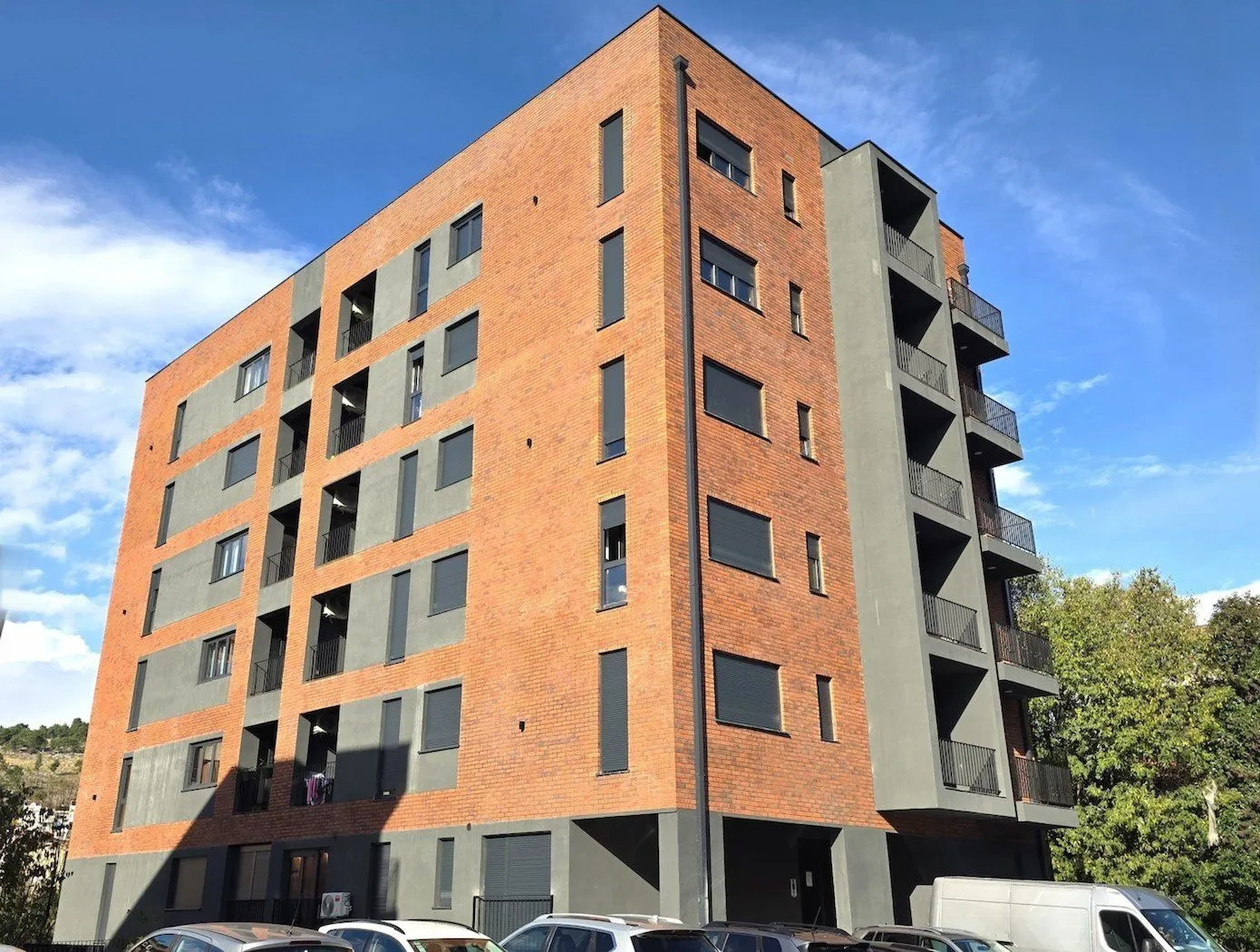 Exterior view of a modern residential building with a brick facade and balconies.