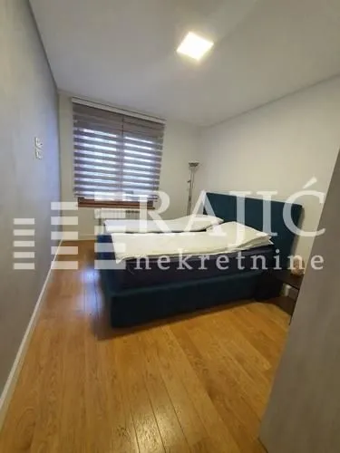 Furnished bedroom with a double bed and wooden flooring.