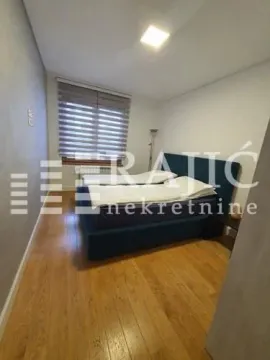 Furnished bedroom with a double bed and wooden flooring. - image 10