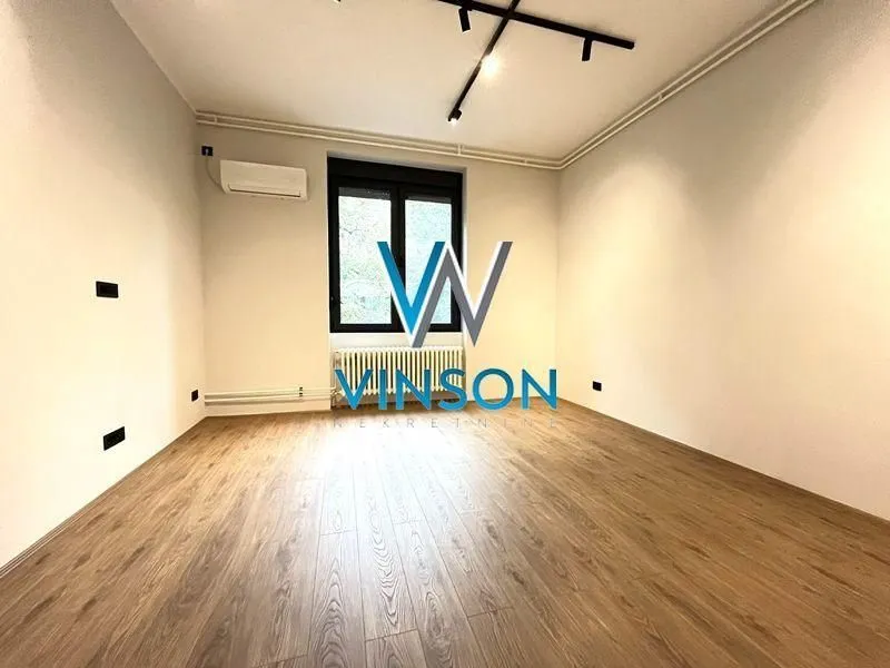 Empty room with laminate flooring, white walls, and an air conditioning unit.