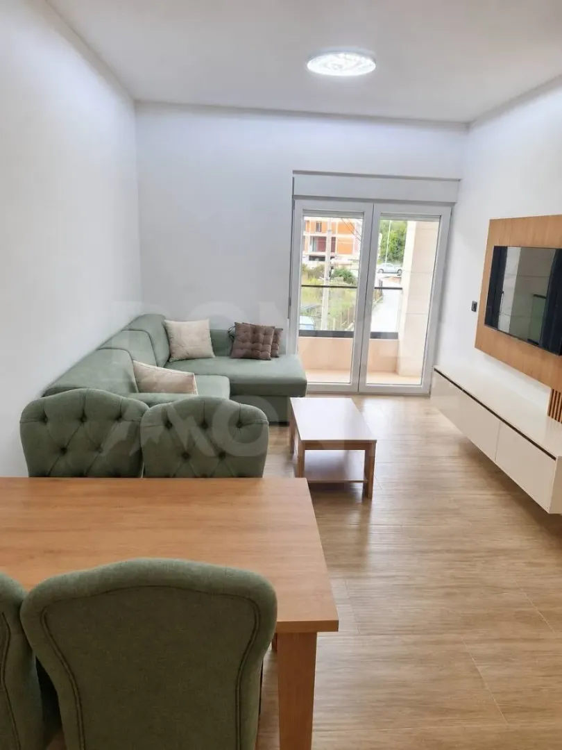 Living room with a sofa, dining table, and TV unit.