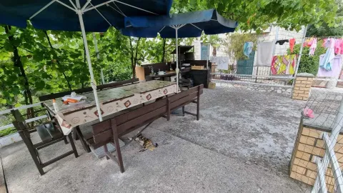Terasa sa drvenim stolom, klupama i suncobranima u dvorištu kuće. - image 5