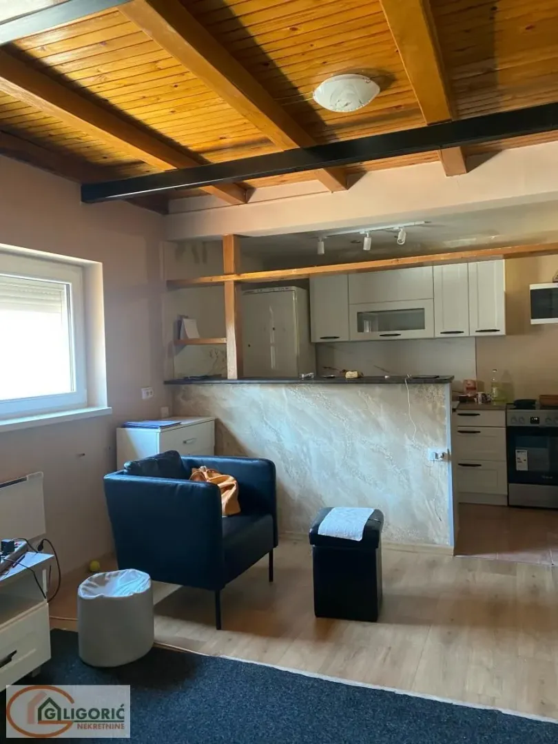 Living room with a wooden ceiling and a view of the kitchen.