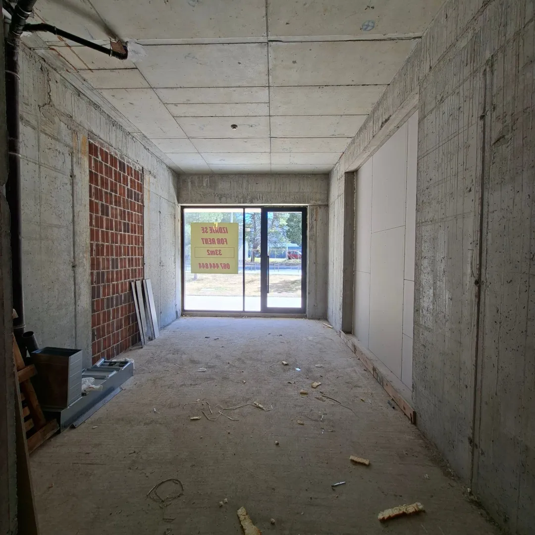 View of an empty commercial space in bare shell condition with a glass storefront.