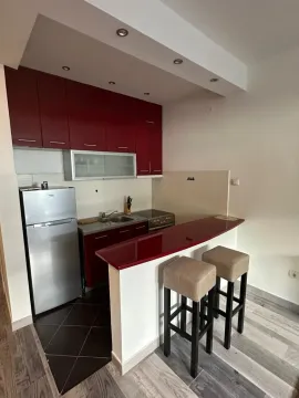 Small kitchen with red cabinets, a breakfast bar, and two bar stools. - image 19