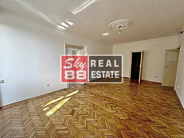 Empty room with wooden parquet flooring and white walls.