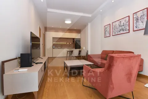 Living room with a sofa, TV unit, and a kitchen in the background. - image 3